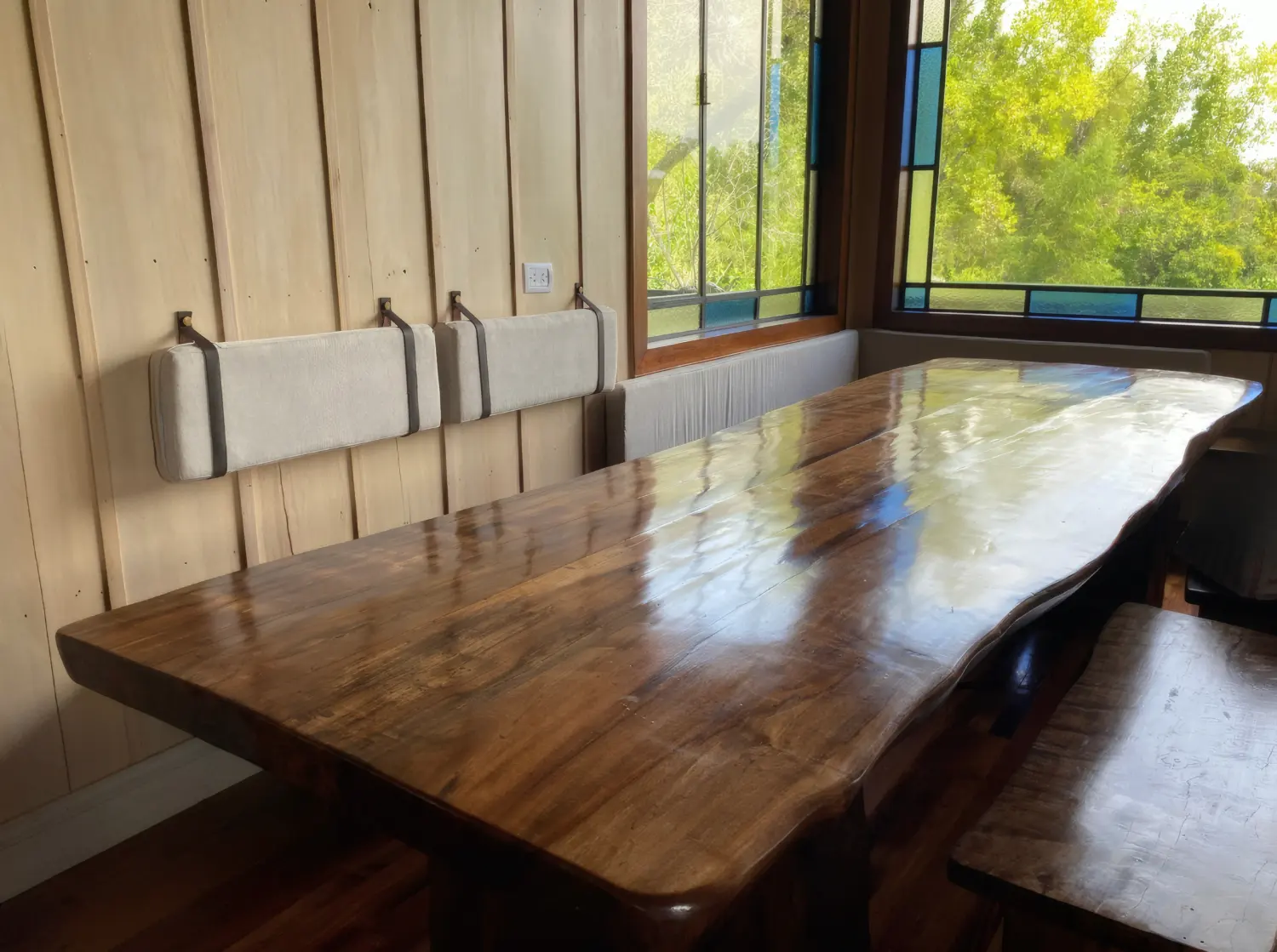 Mesa larga de madera maciza junto al ventanal con vitrales