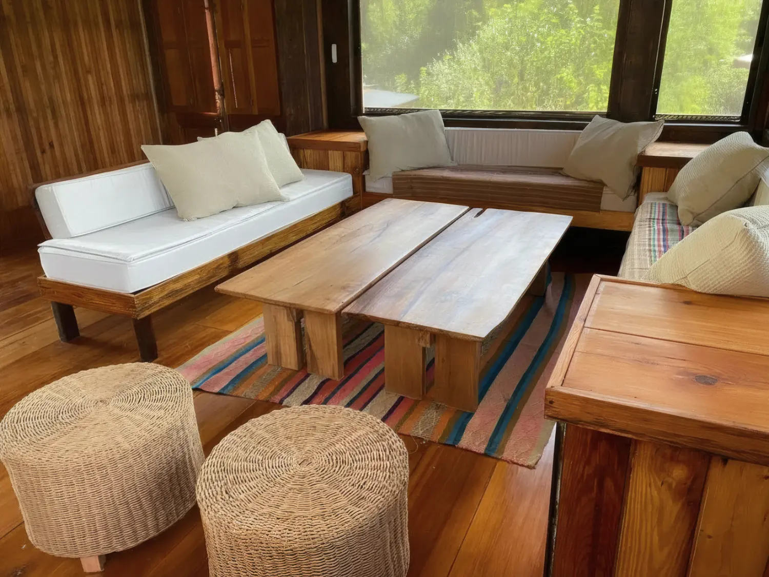 Sillones de madera alrededor de una mesa ratona de tablones, sobre una alfombra a rayas