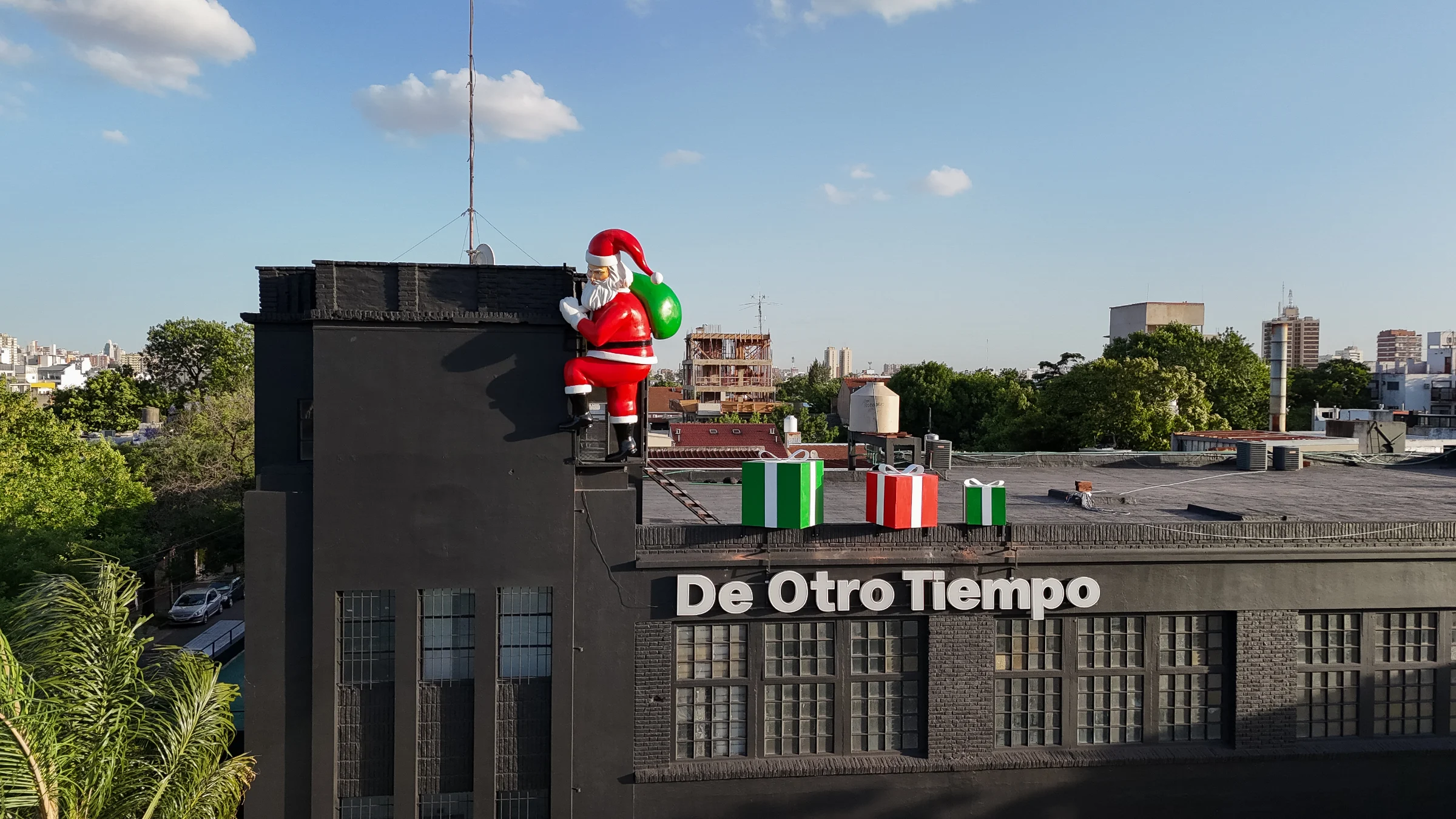 La fachada con las palmeras adelante y la figura arriba